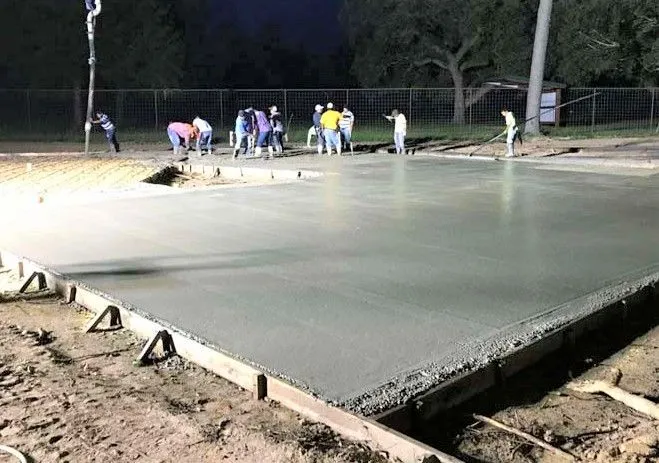 Crew finishing a concrete slab under work lights at night in Houston, TX