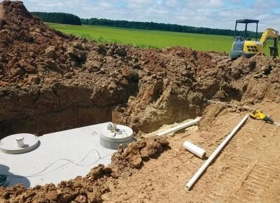 Septic tank set in an open excavation with an excavator standing by in Houston, TX