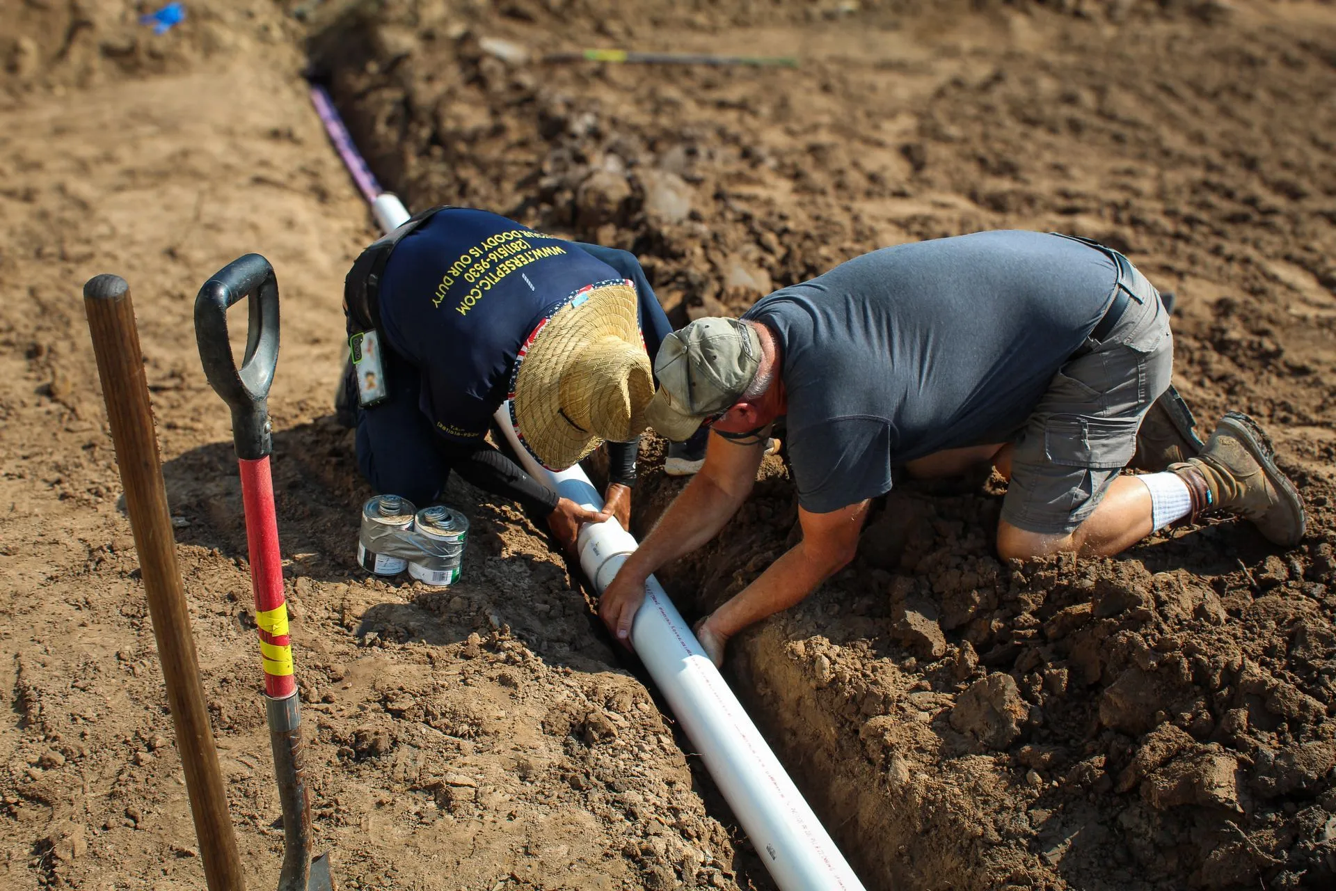Two T.E.R. Septic technicians joining a PVC septic line in an open trench in Houston, TX