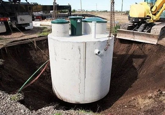 Round concrete septic tank being lowered into an excavated hole in Houston, TX