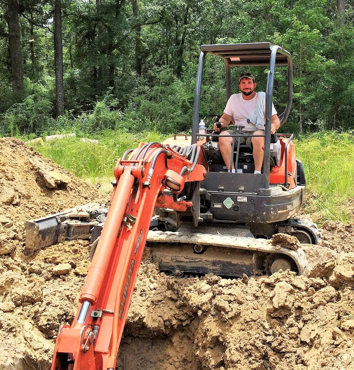 Operator running a compact excavator beside a dug septic trench in Houston, TX
