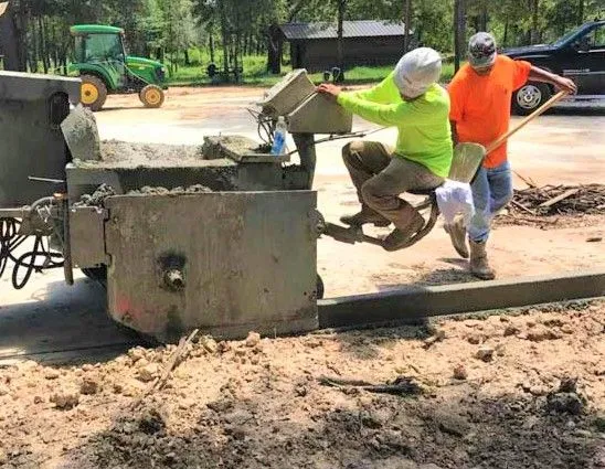 Workers discharging concrete from a mixer into a curb form in Tomball, TX