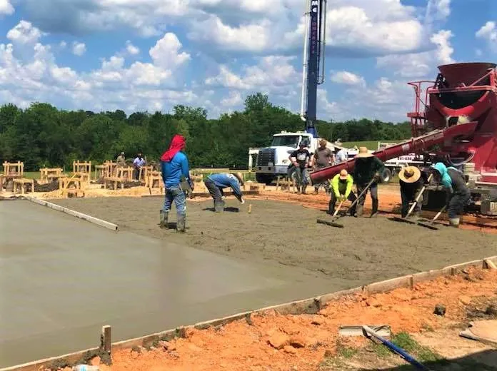 Crew screeding a large concrete slab pour from a pump truck in Tomball, TX